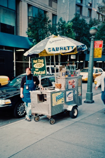 一个穿着蓝色t恤和牛仔裤的男人站在食品车旁边